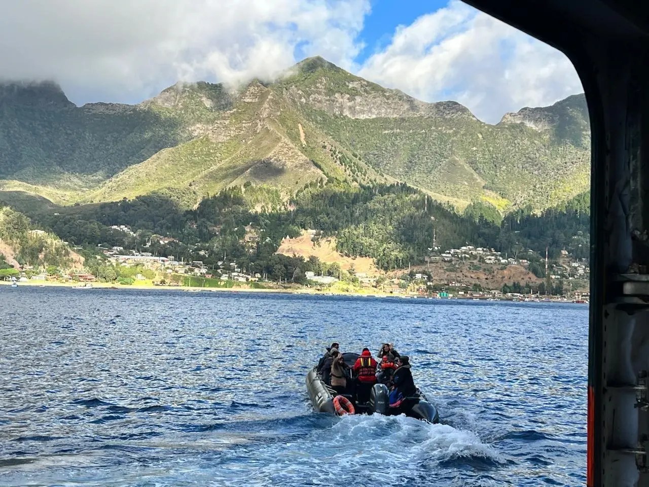 A Zodiac carrying Seabourn Pursuit's medical team heads across the bay toward the green peaks and village of Robinson Crusoe Island